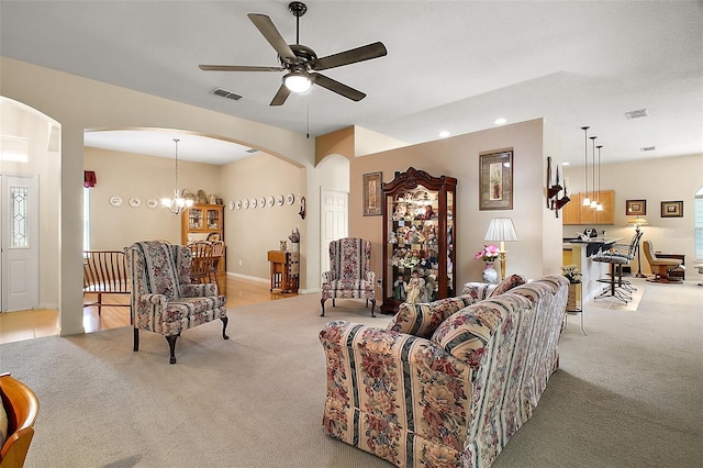 3828 Arbordale Ct, Leesburg, FL 34748 - living area with light carpet, arched walkways, visible vents, and ceiling fan with notable chandelier