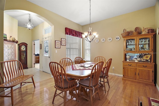 3828 Arbordale Ct, Leesburg, FL 34748 - dining area featuring baseboards, light wood finished floors, arched walkways, and a notable chandelier