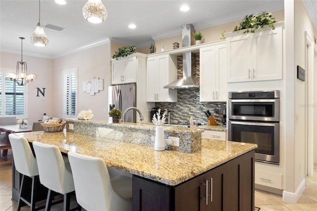 kitchen with a center island with sink, wall chimney exhaust hood, white cabinets, and stainless steel appliances
