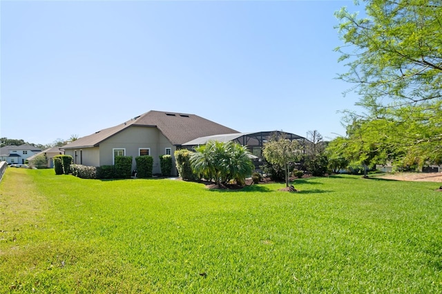 view of side of property with a lanai, a yard, and stucco siding