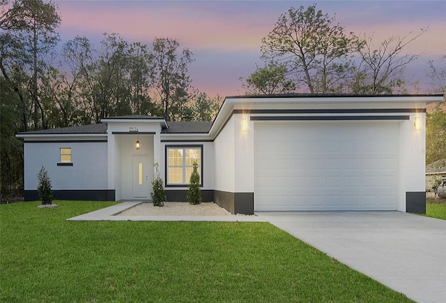 view of front of property with a garage, stucco siding, driveway, and a front lawn