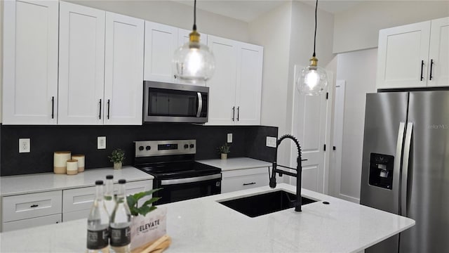 kitchen with a sink, appliances with stainless steel finishes, white cabinets, and decorative light fixtures