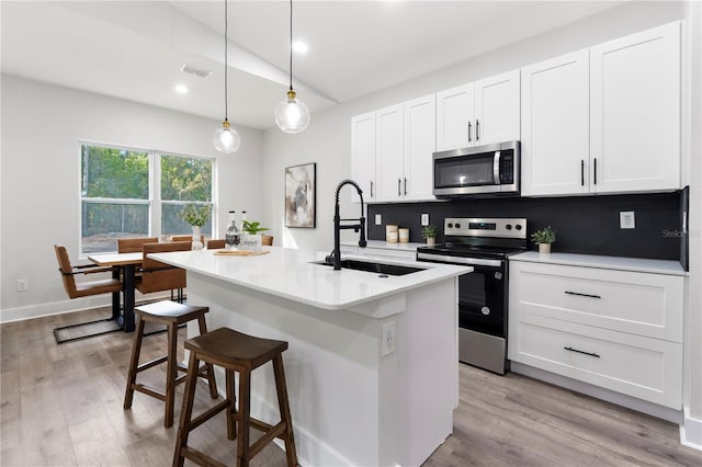 kitchen featuring visible vents, white cabinetry, a sink, vaulted ceiling, and stainless steel appliances