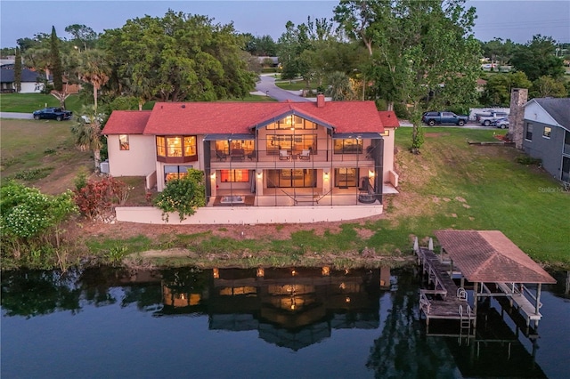 back of property with a lawn, a water view, stairway, and a patio