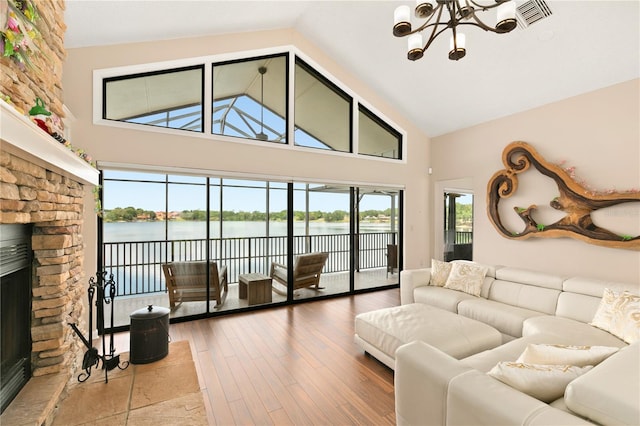 living room featuring a notable chandelier, high vaulted ceiling, visible vents, and a fireplace