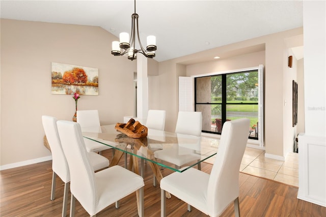 dining room with baseboards, lofted ceiling, wood finished floors, and a chandelier