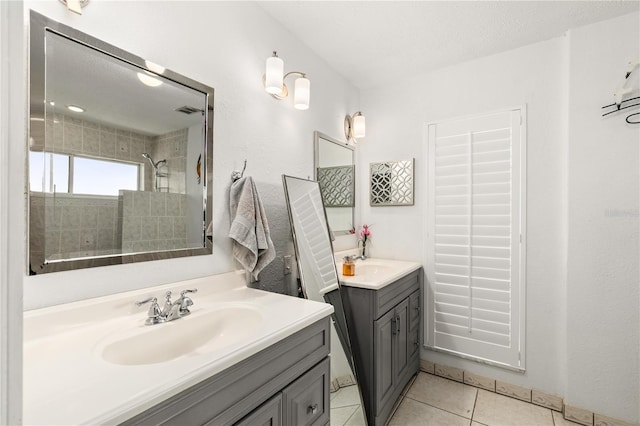 bathroom featuring a tile shower, a sink, tile patterned flooring, two vanities, and visible vents