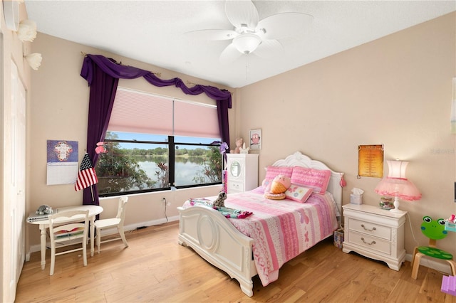 bedroom with baseboards, ceiling fan, a water view, and light wood finished floors