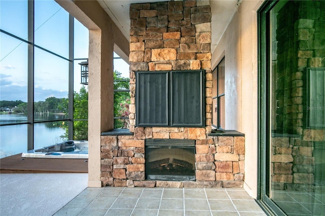 interior space featuring an outdoor hot tub, a water view, and an outdoor stone fireplace