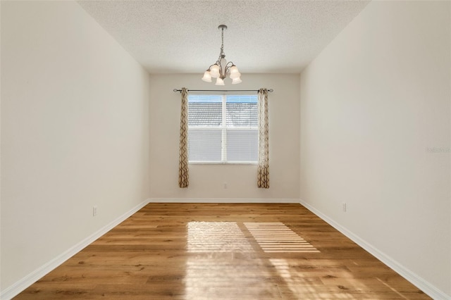 9081 Saint Andrews Way, Mount Dora, FL 32757 - empty room featuring a chandelier, wood finished floors, a textured ceiling, and baseboards