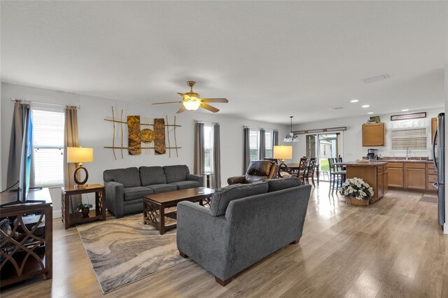 living room featuring light wood-style floors, a ceiling fan, and recessed lighting