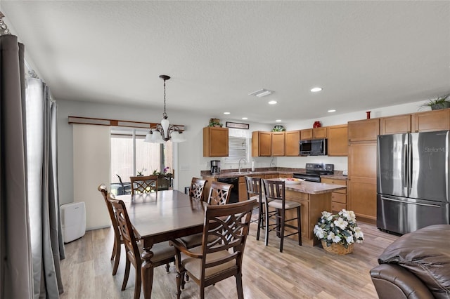 dining space featuring visible vents, an inviting chandelier, a textured ceiling, recessed lighting, and light wood-style flooring