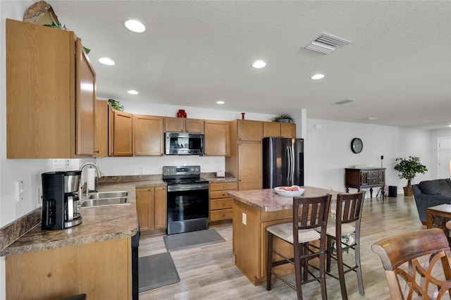 kitchen with a kitchen island, visible vents, a kitchen bar, appliances with stainless steel finishes, and a sink