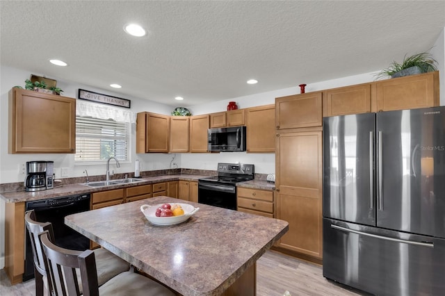 kitchen with a textured ceiling, recessed lighting, a sink, and stainless steel appliances