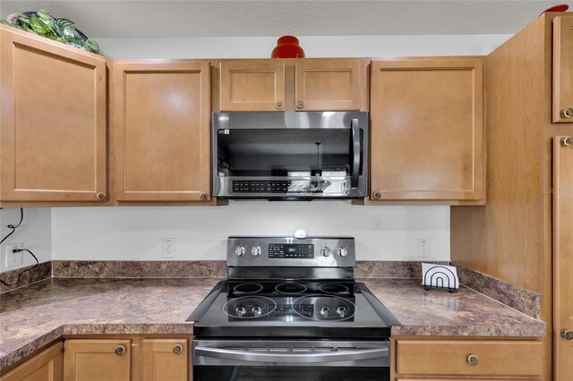 kitchen with stainless steel microwave, range with electric cooktop, and dark countertops