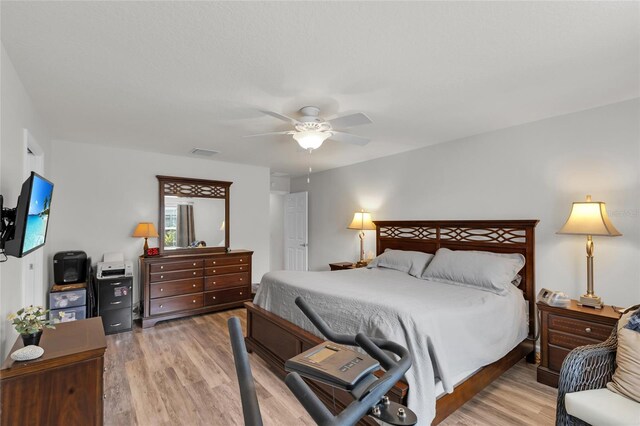 bedroom featuring light wood finished floors, visible vents, and ceiling fan