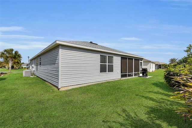 rear view of property with central AC, a sunroom, and a lawn