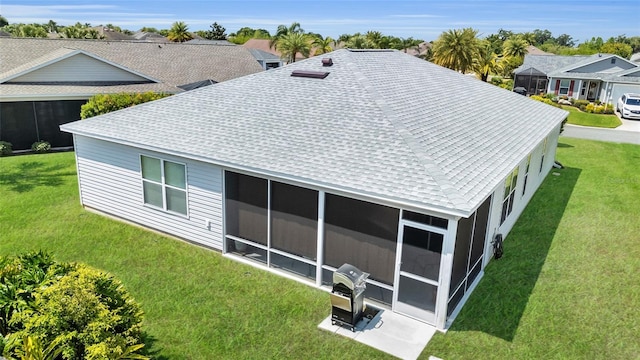 back of house with a sunroom, roof with shingles, and a yard