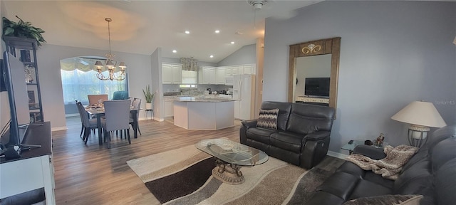 living room with light wood-style flooring, vaulted ceiling, recessed lighting, baseboards, and a notable chandelier