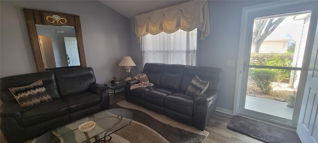 living room featuring a wealth of natural light, vaulted ceiling, wood finished floors, and baseboards