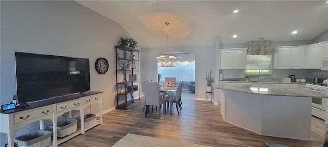 kitchen featuring white appliances, light stone countertops, white cabinets, a chandelier, and lofted ceiling