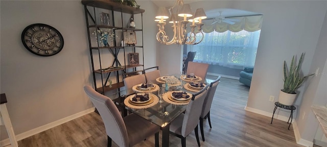 dining space with wood finished floors, ceiling fan with notable chandelier, and baseboards