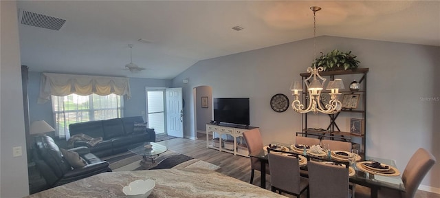 living area with visible vents, ceiling fan with notable chandelier, wood finished floors, and lofted ceiling