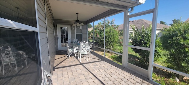 sunroom / solarium with outdoor dining space and a chandelier