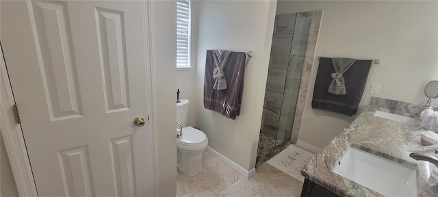 bathroom featuring a shower stall, double vanity, a sink, and toilet