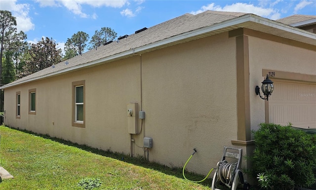 view of side of property with a garage, stucco siding, and a lawn