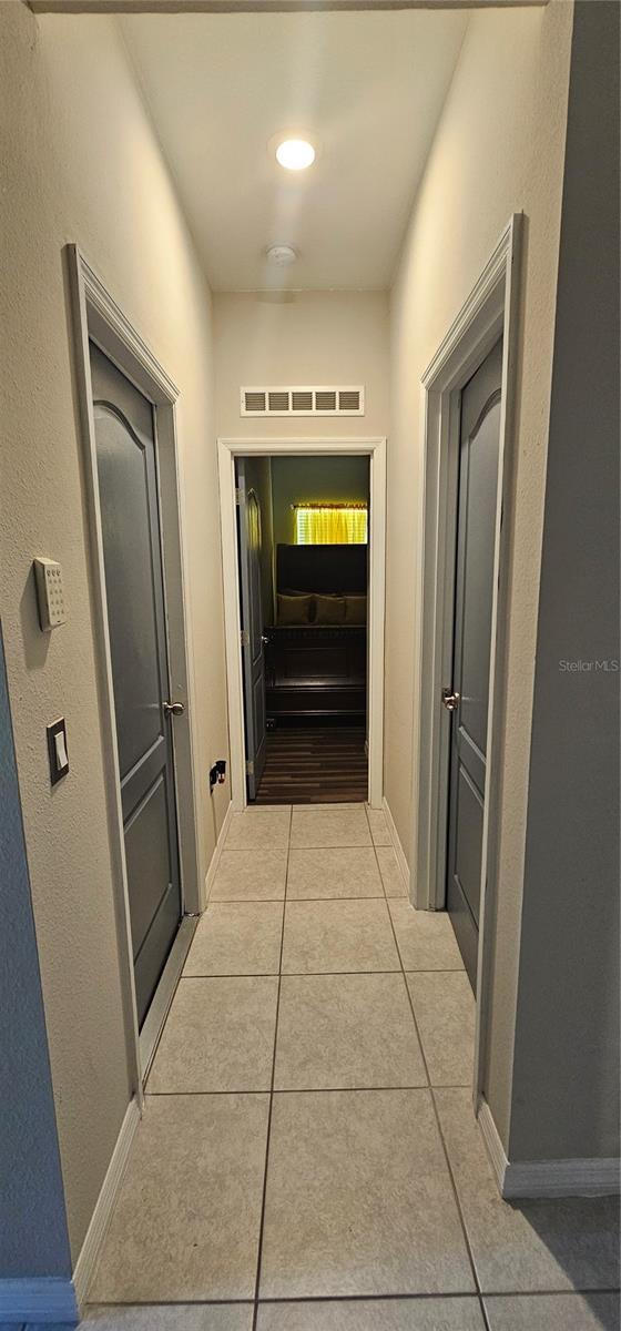 hall with light tile patterned floors, baseboards, and visible vents