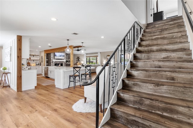 stairs featuring wood finished floors, visible vents, lofted ceiling, and recessed lighting