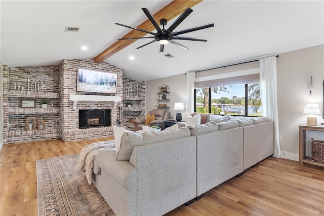 living area featuring a ceiling fan, visible vents, wood finished floors, vaulted ceiling with beams, and a brick fireplace