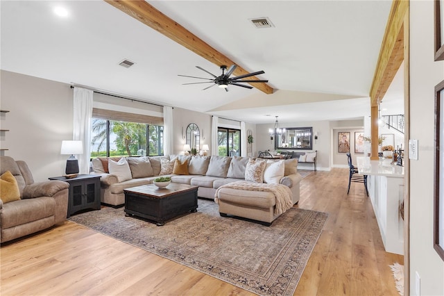 living room featuring visible vents, light wood finished floors, lofted ceiling with beams, and ceiling fan with notable chandelier