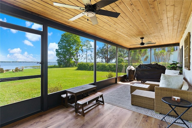 sunroom with a water view, a wealth of natural light, and a ceiling fan