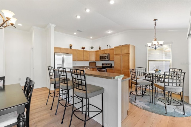 kitchen featuring light wood finished floors, stainless steel appliances, a kitchen breakfast bar, a chandelier, and crown molding