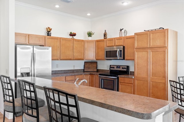 kitchen with stainless steel appliances, a sink, visible vents, a kitchen bar, and ornamental molding