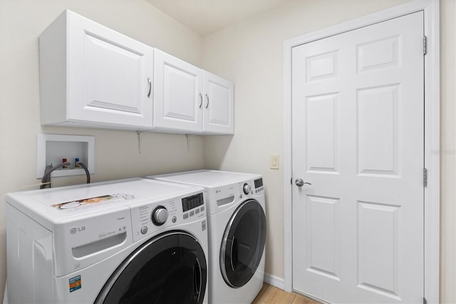 laundry area with washing machine and clothes dryer, baseboards, light wood-style floors, and cabinet space