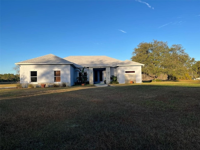 ranch-style home featuring stucco siding and a front lawn