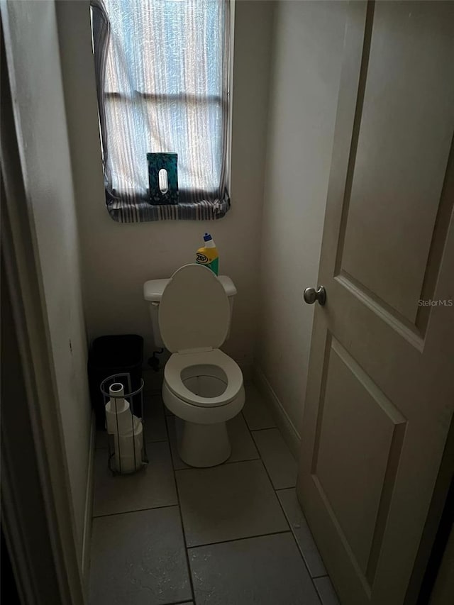 bathroom with toilet, tile patterned floors, and baseboards