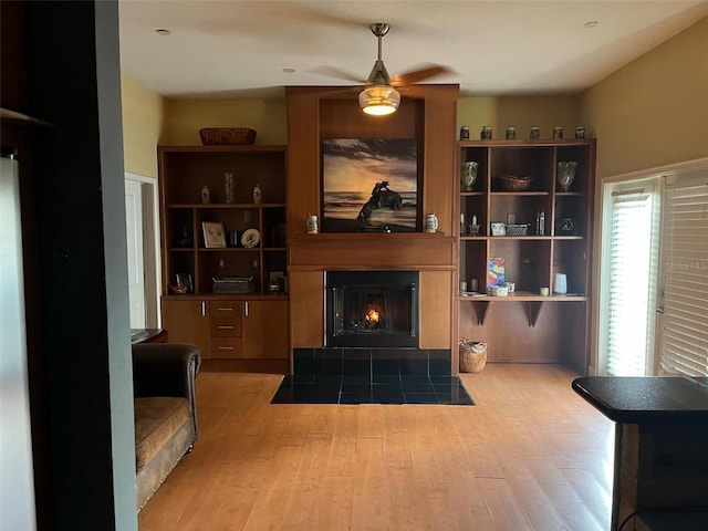 living room featuring a fireplace with flush hearth, wood finished floors, and a ceiling fan
