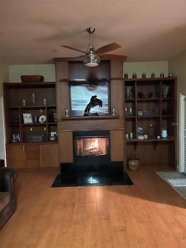 living room featuring a wood stove, ceiling fan, and wood finished floors