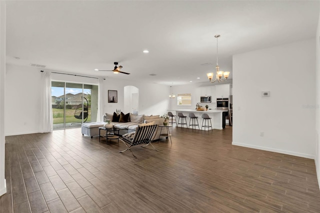 living room with recessed lighting, dark wood-type flooring, visible vents, arched walkways, and ceiling fan with notable chandelier