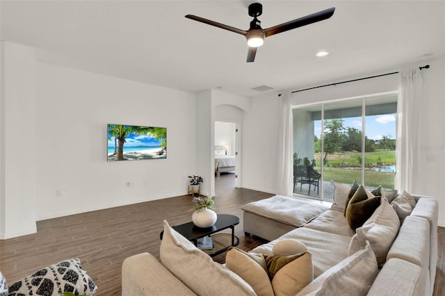living room with visible vents, baseboards, arched walkways, a ceiling fan, and wood finished floors