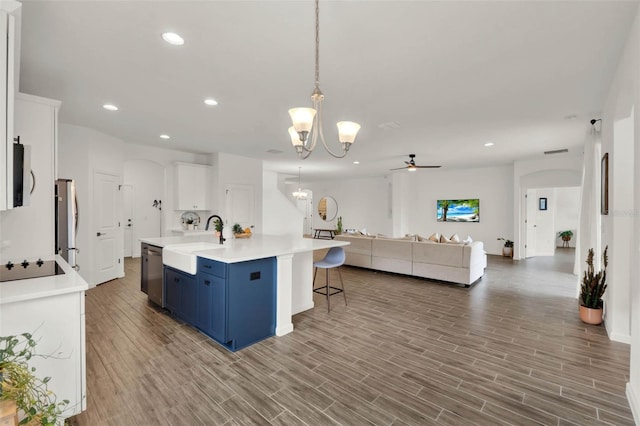 kitchen with ceiling fan with notable chandelier, blue cabinets, a sink, stainless steel appliances, and open floor plan