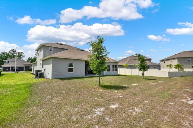 rear view of house with roof with shingles, central AC, fence, and a lawn
