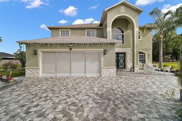 54 Andora Ct, Kissimmee, FL 34758 - view of front facade with an attached garage, stone siding, decorative driveway, and stucco siding