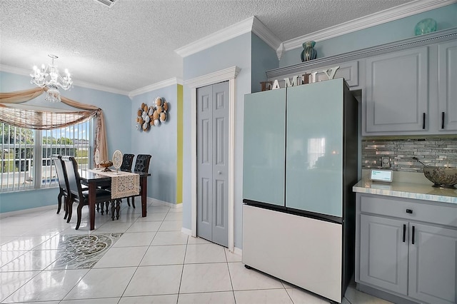 54 Andora Ct, Kissimmee, FL 34758 - kitchen featuring freestanding refrigerator, a chandelier, a textured ceiling, gray cabinetry, and decorative backsplash