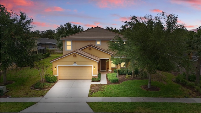 view of front of house with a yard, stucco siding, a tile roof, an attached garage, and driveway