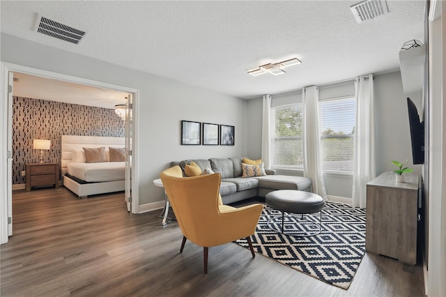 living room featuring visible vents, baseboards, wood finished floors, and a textured ceiling